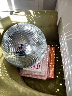 a disco ball sitting on top of a green chair next to a notebook and book