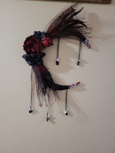 a clock made out of feathers and flowers hanging on the side of a white wall