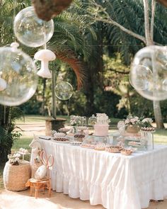 a table topped with lots of cake next to bubble filled balloons in the shape of bubbles