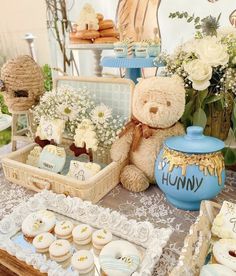 a teddy bear sitting on top of a table next to cupcakes and cookies