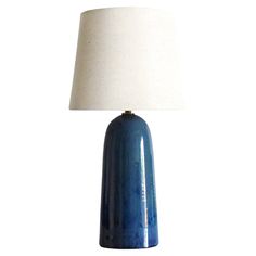 a blue table lamp with a white shade on the base and a light in the middle