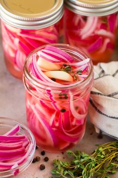 pickled red onions in a mason jar with herbs