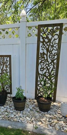 three planters with plants in them sitting on the ground next to a white fence