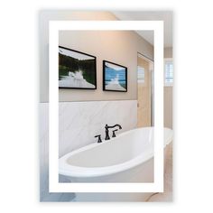 a white bath tub sitting in a bathroom next to two pictures hanging on the wall