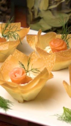 small appetizers are arranged on a plate with dill sprigs and carrots