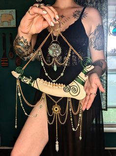 a woman in a black dress with tattoos and chains on her body holding a necklace