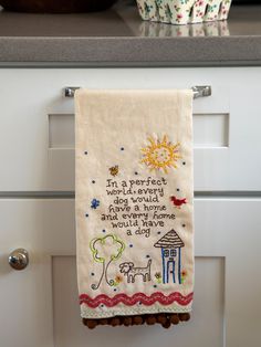 an embroidered tea towel hanging on a kitchen cabinet