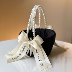 a black bag with pearls and a white ribbon tied around it on top of a table