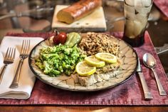 a plate with meat, broccoli, rice and lemon wedges on it