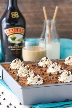 a pan filled with cookies and whipped cream on top of a table next to bottles of milk