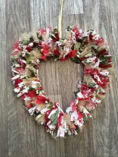 a wreath with red and white flowers hanging on a wooden wall next to a pair of scissors