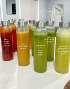 seven bottles with different types of liquid in them on a white countertop next to a mirror