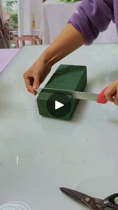 a woman is cutting something with a pair of scissors on top of a countertop