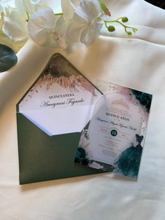 an elegant wedding suite is displayed on a table with white flowers and green envelopes