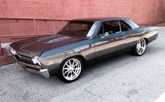 an old car is parked in front of a brick wall and has chrome rims