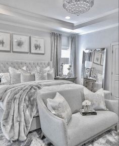 black and white photograph of a bedroom with a bed, chair, mirror and pictures on the wall