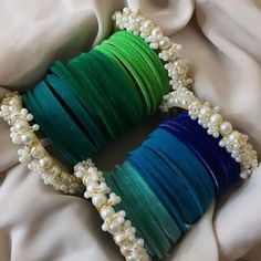 several different colored bracelets with pearls and beads on top of a white cloth covered surface