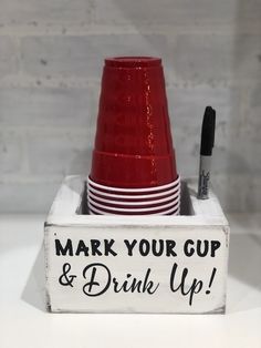 a red cup and some white plates in a holder with the words mark your cup & drink up