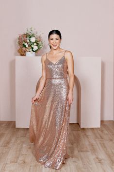 a woman standing in a room wearing a long dress with sequins on it