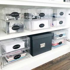 some clear plastic bins with labels and file folders in them on a white shelf