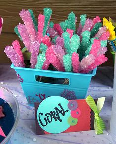 there is a blue container with pink and green candy sticks in it on the table