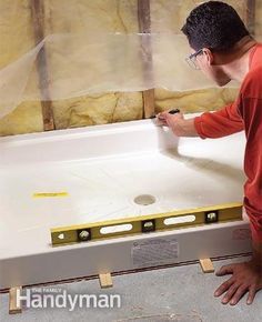 a man in an orange shirt working on a bathtub