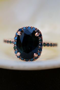 a ring with a blue stone surrounded by black and white diamonds on top of it