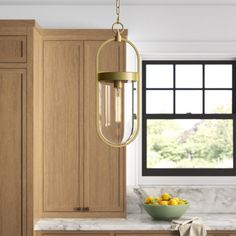 a kitchen with wooden cabinets, marble counter tops and a gold chandelier hanging from the ceiling