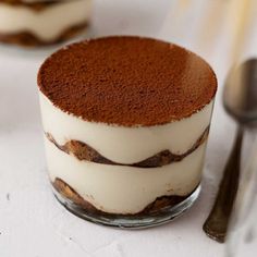 two desserts are sitting on a table with spoons and forks in front of them