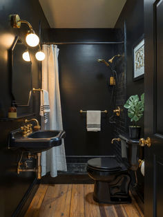 a bathroom with black walls and wood floors