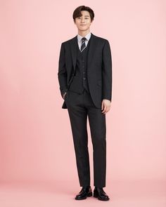 a young man in a suit and tie poses for the camera on a pink background