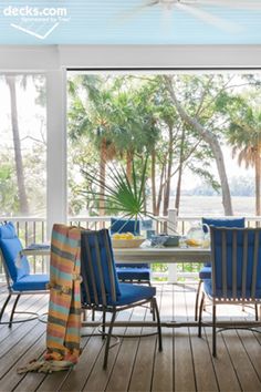 a dining room table with blue chairs and a view of the ocean from it's deck