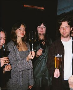 a group of people standing next to each other holding wine glasses in front of them