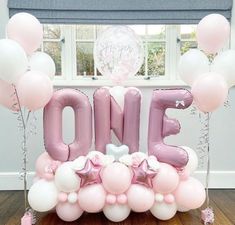 the balloon letters are pink and white with stars on them, along with balloons that spell out the word one