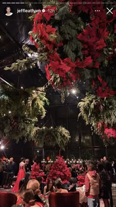 people are sitting at tables with red flowers hanging from the ceiling and decorations on the ceiling