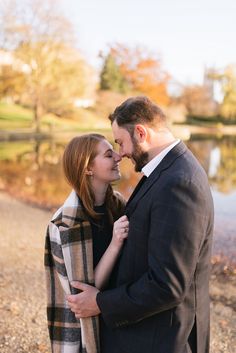 a man and woman standing next to each other in front of a body of water