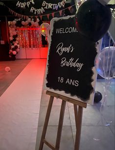 a welcome sign in front of a party with balloons and streamers on the wall