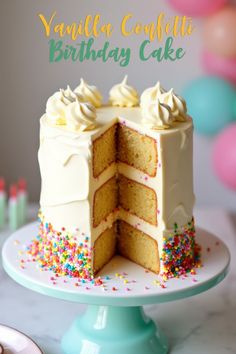 a vanilla cake with white frosting and sprinkles on a blue pedestal