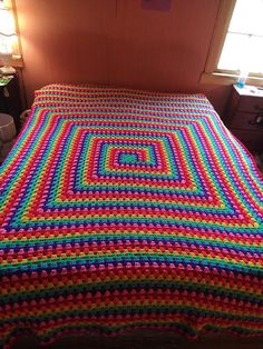 a crocheted bedspread made with multicolored yarns on a bed