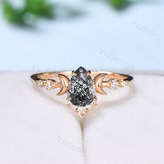 a ring with a black diamond and white diamonds on the side, sitting on top of a