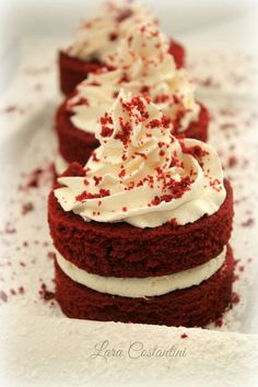 three red velvet cakes with white frosting and sprinkles