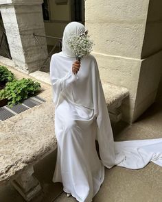 a woman dressed in white is sitting on the steps with her back to the camera