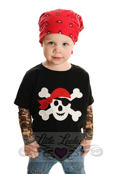 a little boy wearing a pirate shirt and bandanna hat with his hands in his pockets