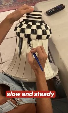 a man is painting a vase with black and white checkerboard designs on it