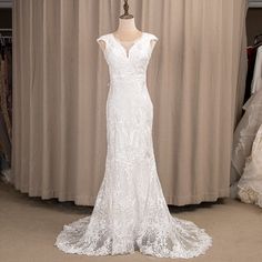 a white wedding dress on display in front of a curtained room with mannequins