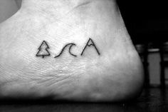 a person with a small tattoo on their foot that says aca and is in the shape of a triangle