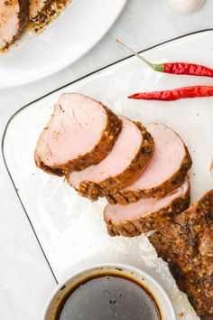 slices of meat and sauce on a plate next to some chili peppers, garlic bread and an eggplant