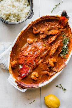 the dish is covered with meat and sauce, next to some lemons on the table