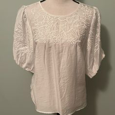 Nwot Satiny Embroidered Top With Puff Sleeves. Spare Button Still Attached Size Large Approximate Measurements Below: Width Under Arms 21.5” Length 24” White Feminine Embroidered Cotton Top, White Puff Sleeve Tops With Embroidered Sleeves, Cream Embroidered Peasant Blouse, Spring Embroidered Cotton Top With 3/4 Sleeves, White Embroidered Top With Short Sleeves, Relaxed Fit, Top With Puff Sleeves, Embroidered Top, Puff Sleeves, Puff Sleeve