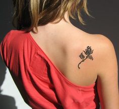 a woman with a rose tattoo on her upper back shoulder and arm, looking to the side